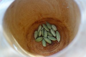 green cardamon pods in a wooden mortar